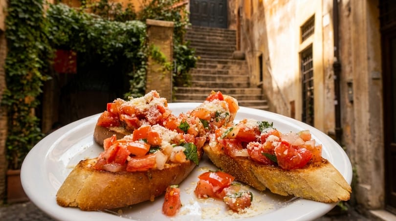 Bruschetta with diced tomatoes, basil, and cheese on a white plate in an Italian alleyway.