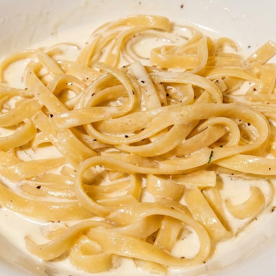 Creamy fettuccine alfredo with black pepper in a white bowl.